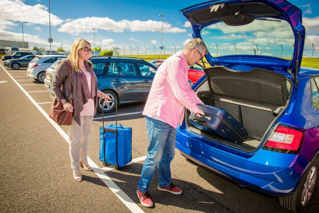 Couple loading luggage into a blue car